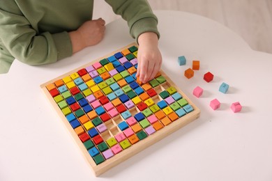 Photo of Motor skills development. Little boy playing with Times table tray indoors, closeup