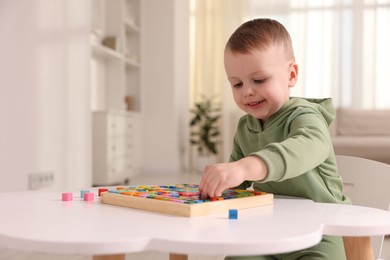 Photo of Motor skills development. Little boy playing with Times table tray indoors