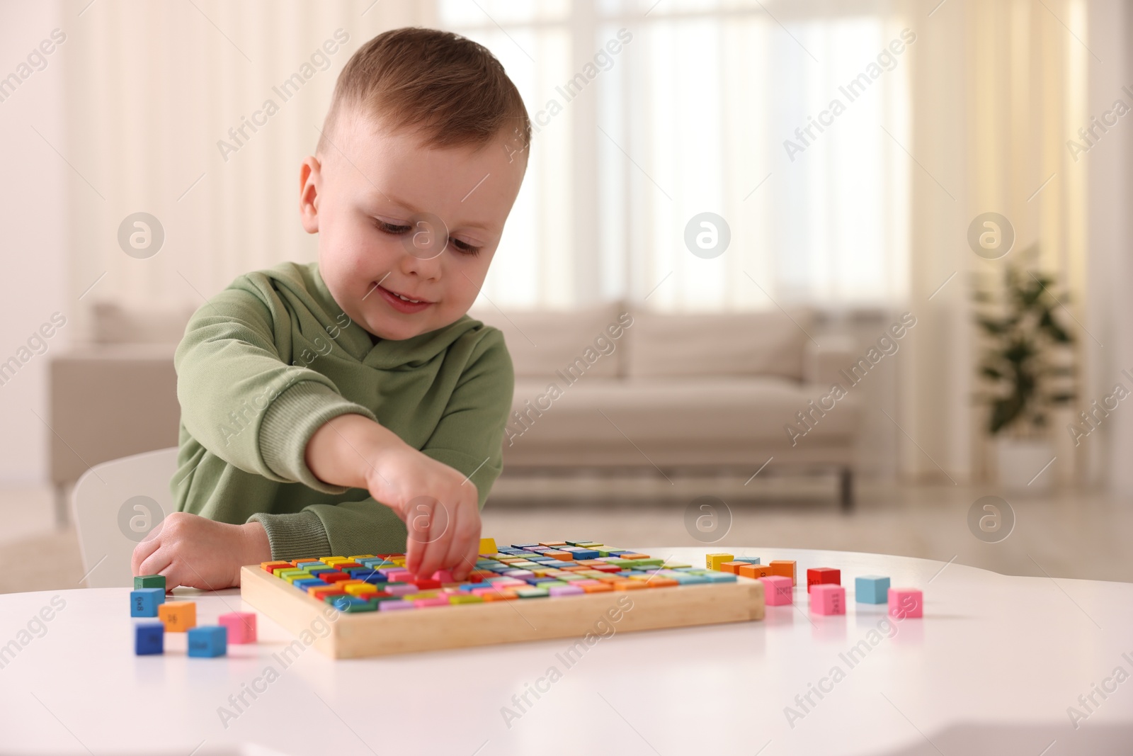 Photo of Motor skills development. Little boy playing with Times table tray indoors