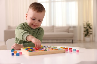 Motor skills development. Little boy playing with Times table tray indoors