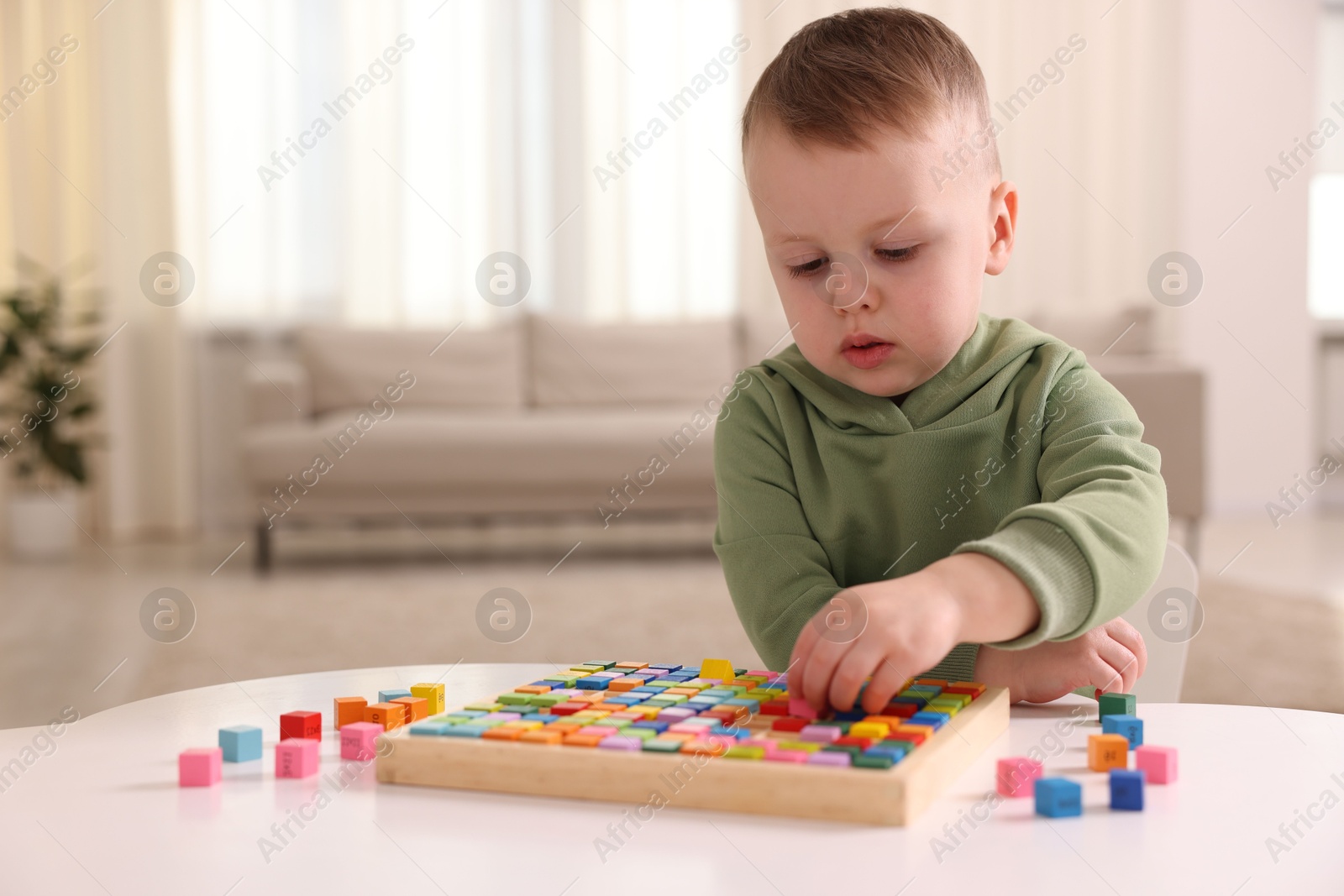 Photo of Motor skills development. Little boy playing with Times table tray indoors