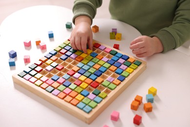 Photo of Motor skills development. Little boy playing with Times table tray indoors, closeup