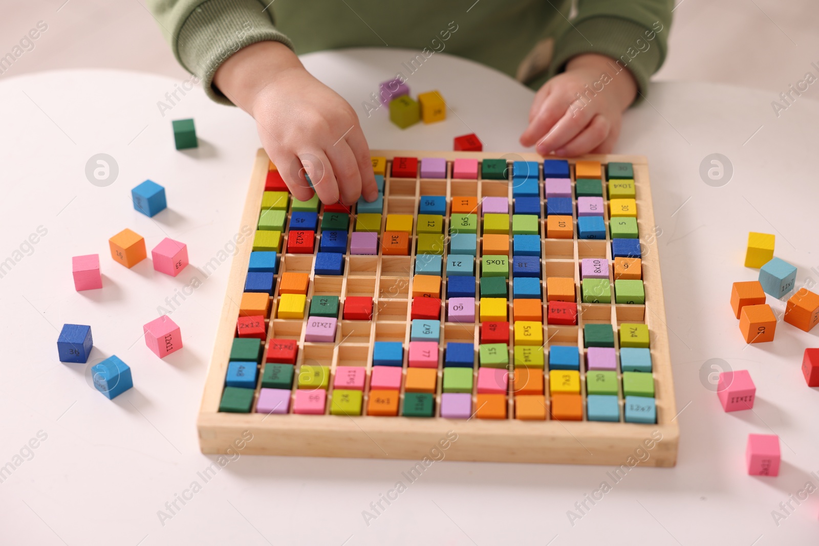 Photo of Motor skills development. Little boy playing with Times table tray indoors, closeup