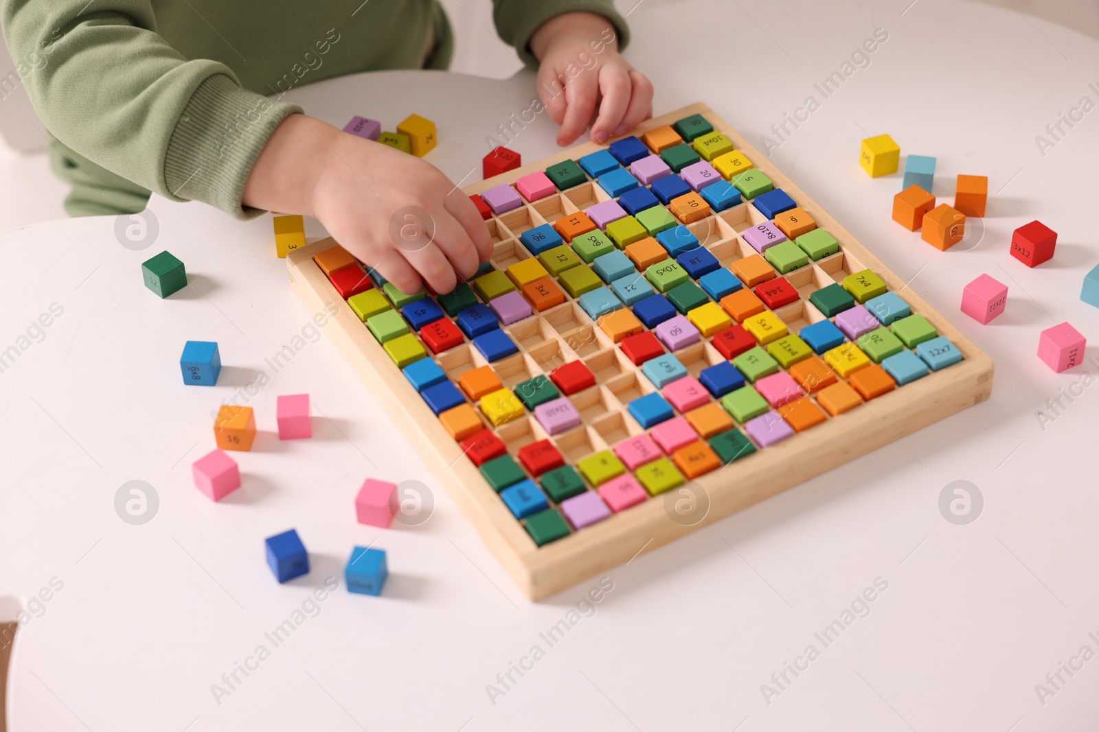 Photo of Motor skills development. Little boy playing with Times table tray indoors, closeup