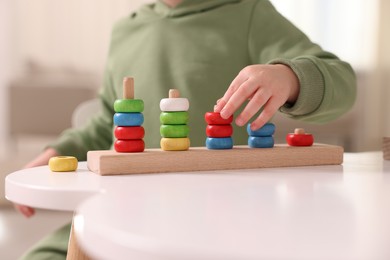 Photo of Motor skills development. Little boy playing with stacking toy at white table indoors, closeup