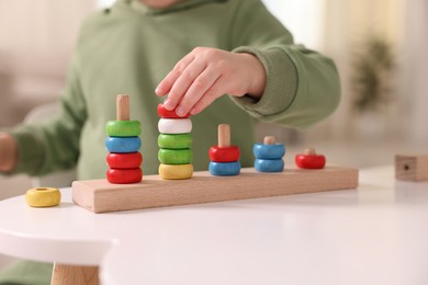 Motor skills development. Little boy playing with stacking toy at white table indoors, closeup