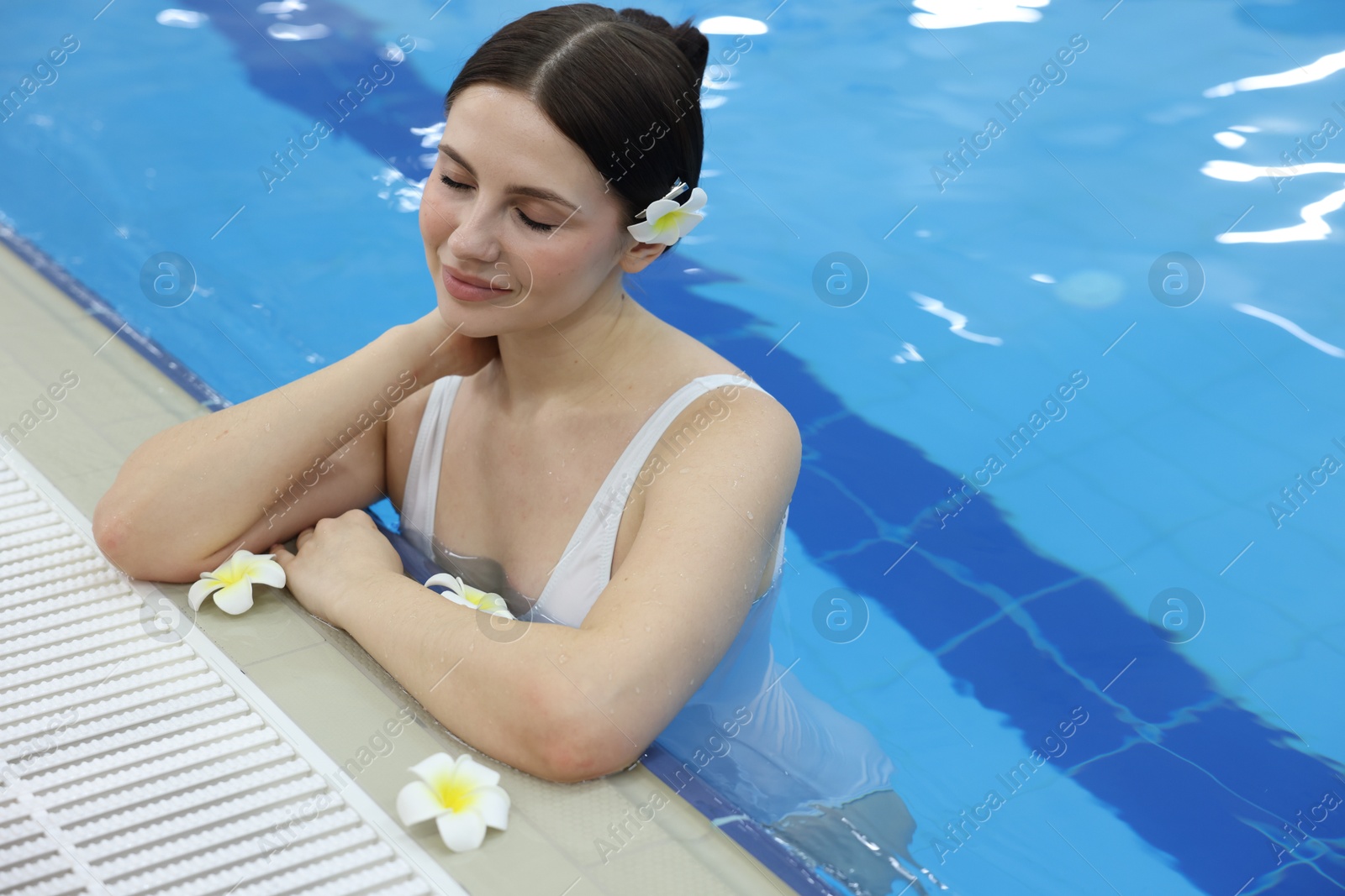 Photo of Beautiful young woman in indoor swimming pool. Space for text