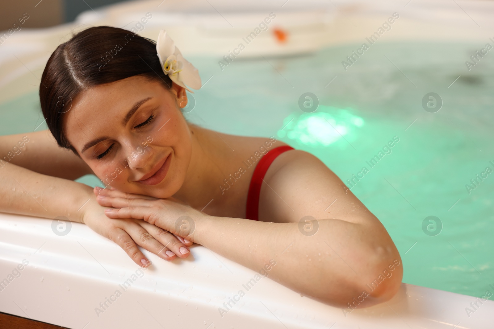 Photo of Beautiful woman relaxing in hot tub indoors