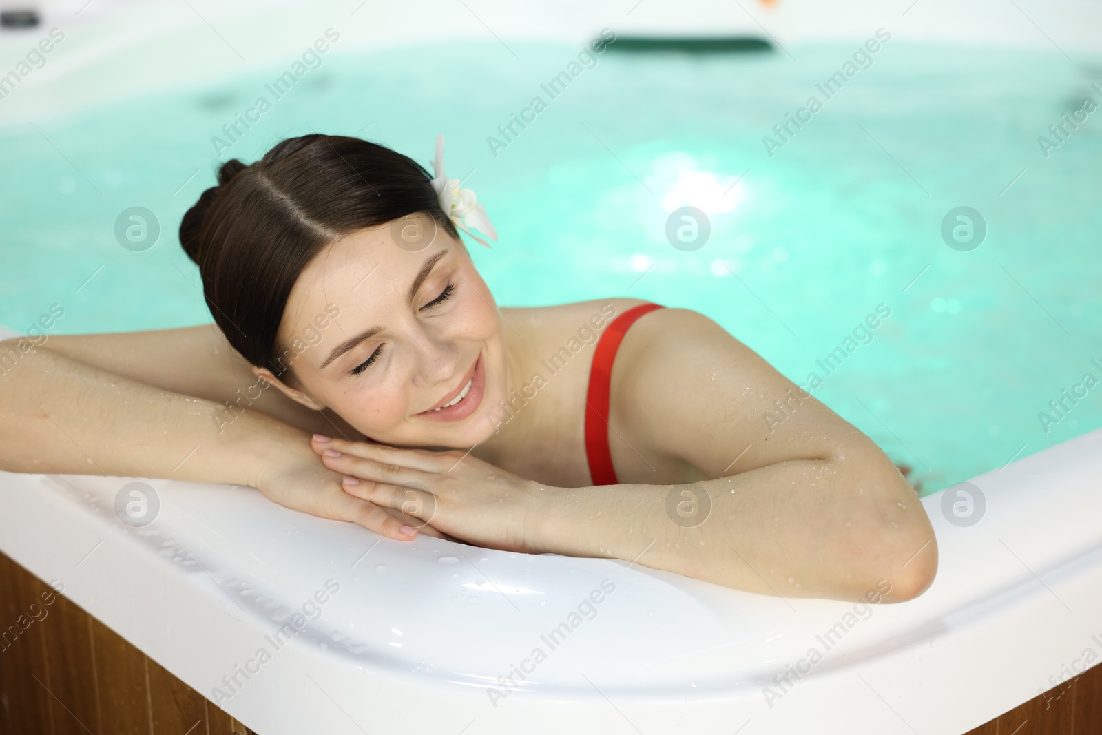 Photo of Beautiful woman relaxing in hot tub indoors