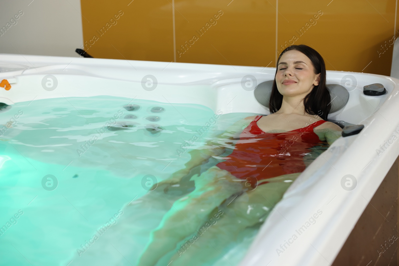 Photo of Beautiful woman relaxing in hot tub indoors. Space for text