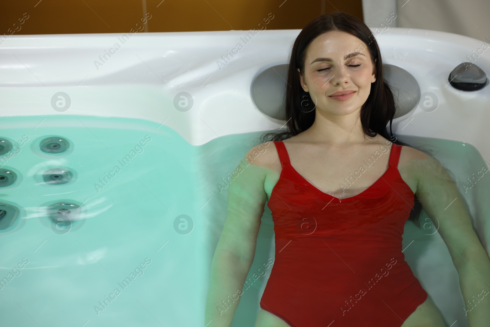 Photo of Beautiful woman relaxing in hot tub indoors. Space for text