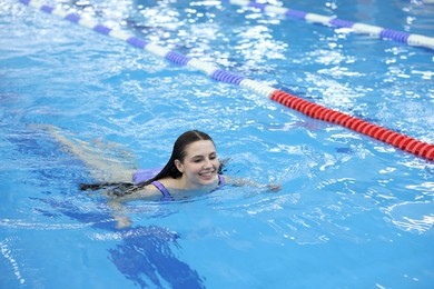 Photo of Beautiful young woman swimming in indoor pool