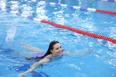 Beautiful young woman swimming in indoor pool