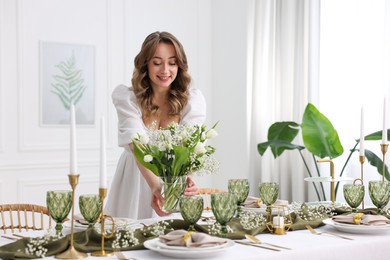 Happy young woman setting table for dinner at home