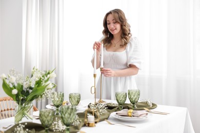 Photo of Happy young woman setting table for dinner at home