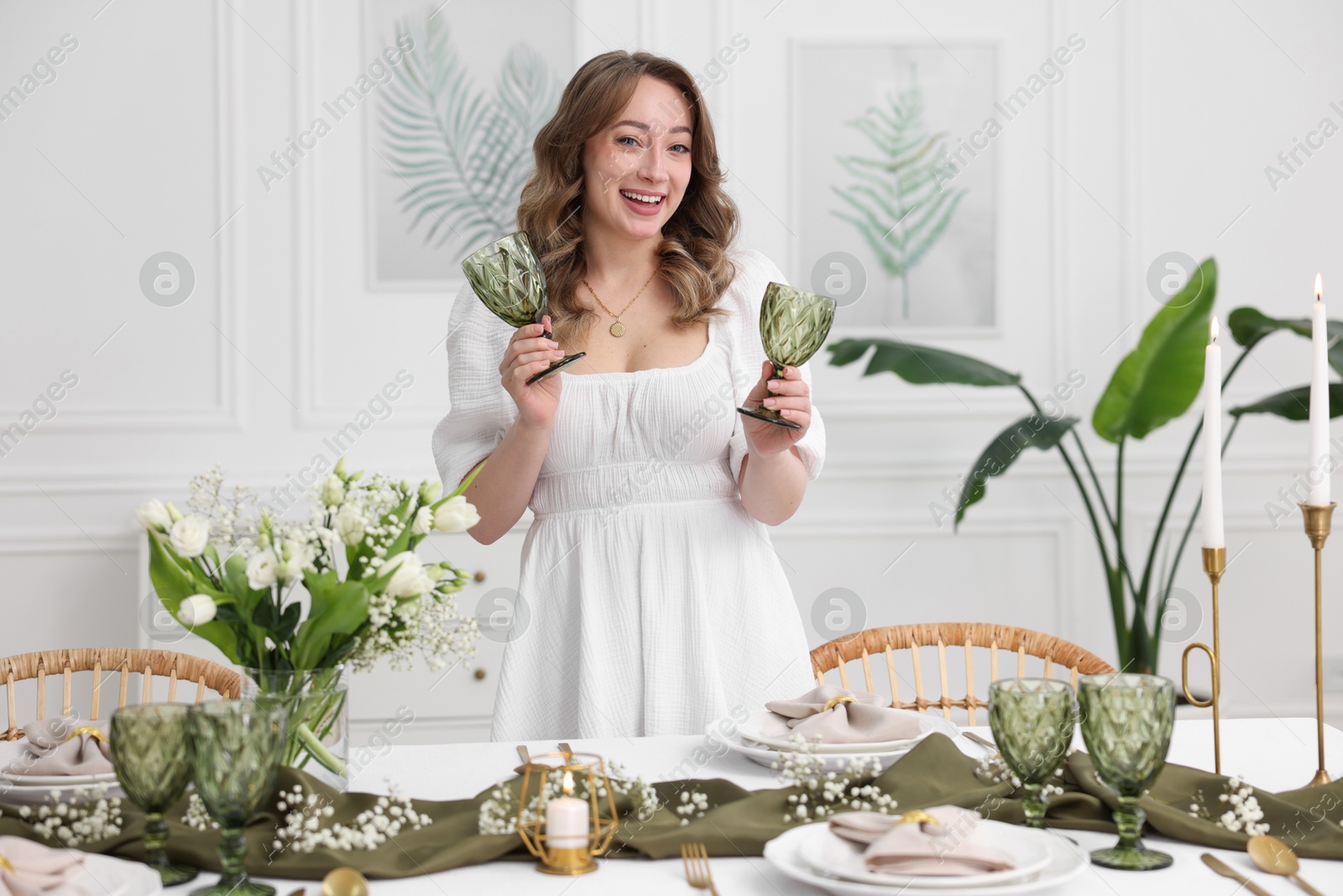 Photo of Happy young woman setting table for dinner at home