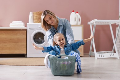 Photo of Mother and daughter having fun while doing laundry together at home