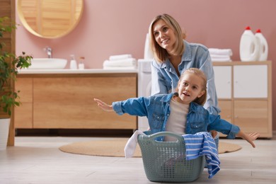 Photo of Mother and daughter having fun while doing laundry together at home