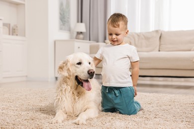 Photo of Little boy with cute dog on carpet at home