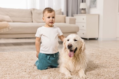 Photo of Little boy with cute dog on carpet at home