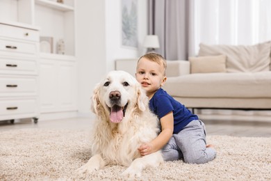 Little boy with cute dog on carpet at home