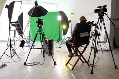 Photo of Man working in modern film studio with professional equipment, back view