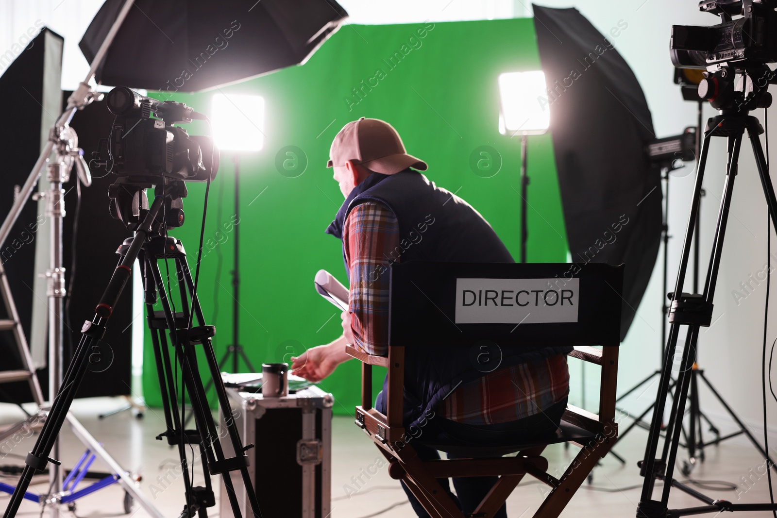 Photo of Movie director sitting on chair in modern film studio, back view