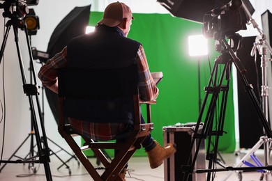 Photo of Movie director sitting on chair in modern film studio, back view