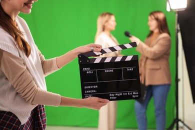 Photo of Second assistant camera holding clapperboard in front of people in modern film studio, selective focus