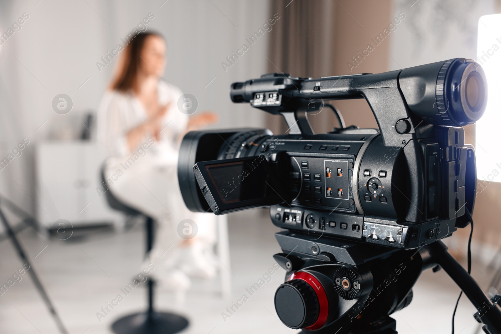 Photo of Woman sitting on chair and working in film studio, focus on camera