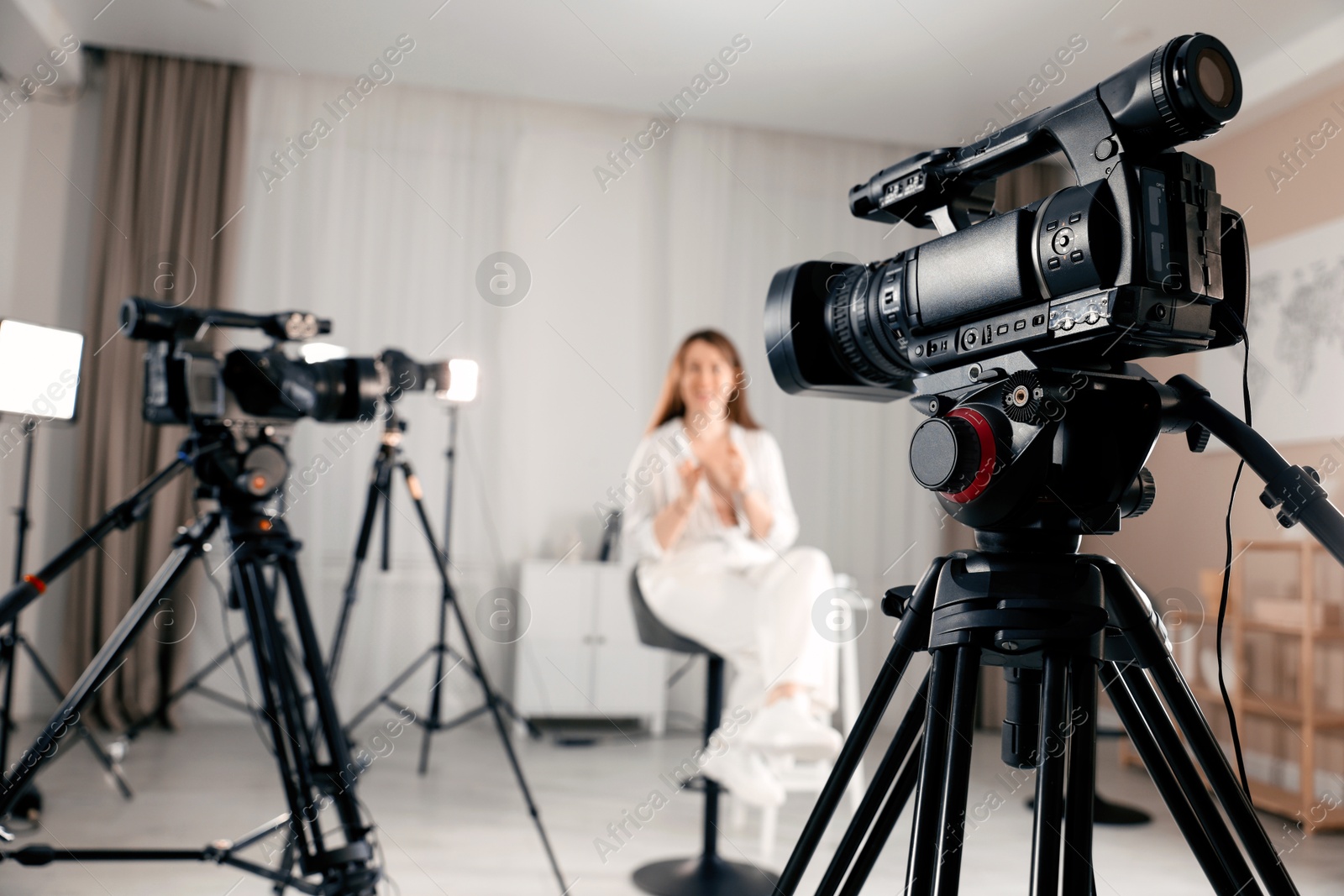 Photo of Woman sitting on chair and working in film studio, focus on camera