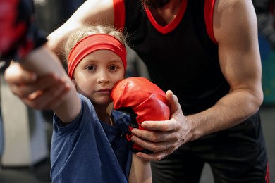 Girl in protective gloves having boxing practice with her coach at training center