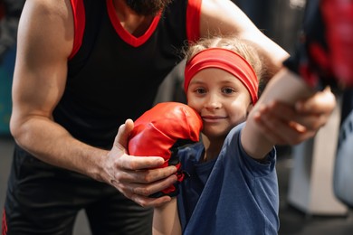 Girl in protective gloves having boxing practice with her coach at training center