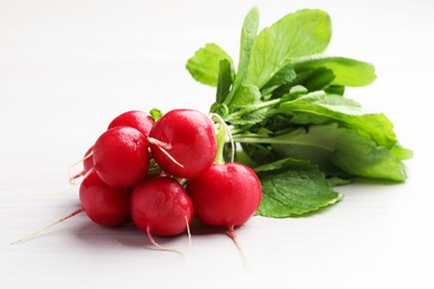 Photo of Bunch of fresh radishes on white wooden table, closeup