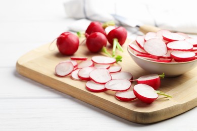 Photo of Fresh whole and cut radishes on white wooden table, closeup
