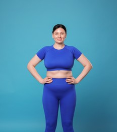 Photo of Plus size woman in gym clothes on light blue background