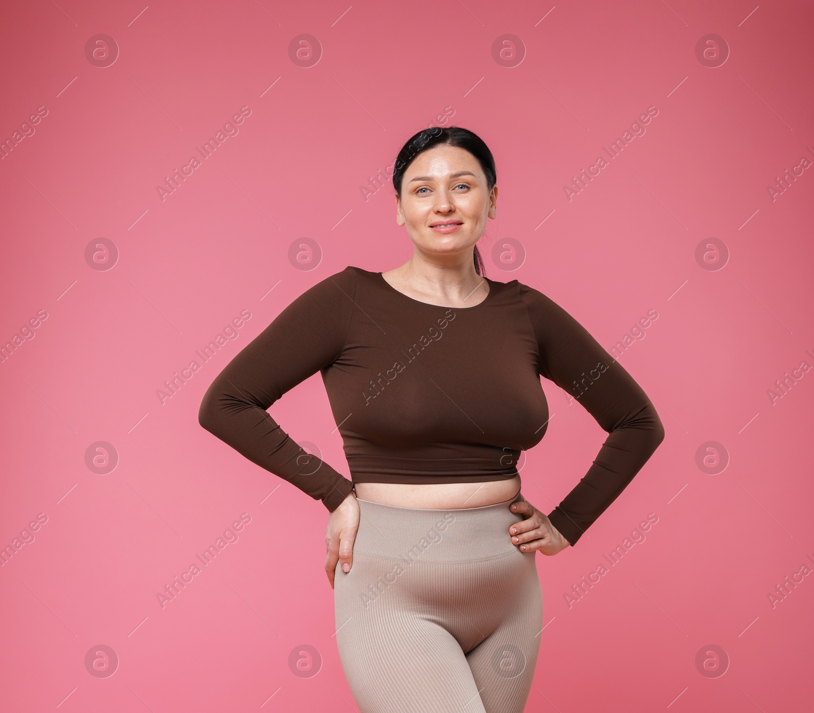 Plus size woman in gym clothes on pink background Photo of Plus size woman in gym clothes on pink background