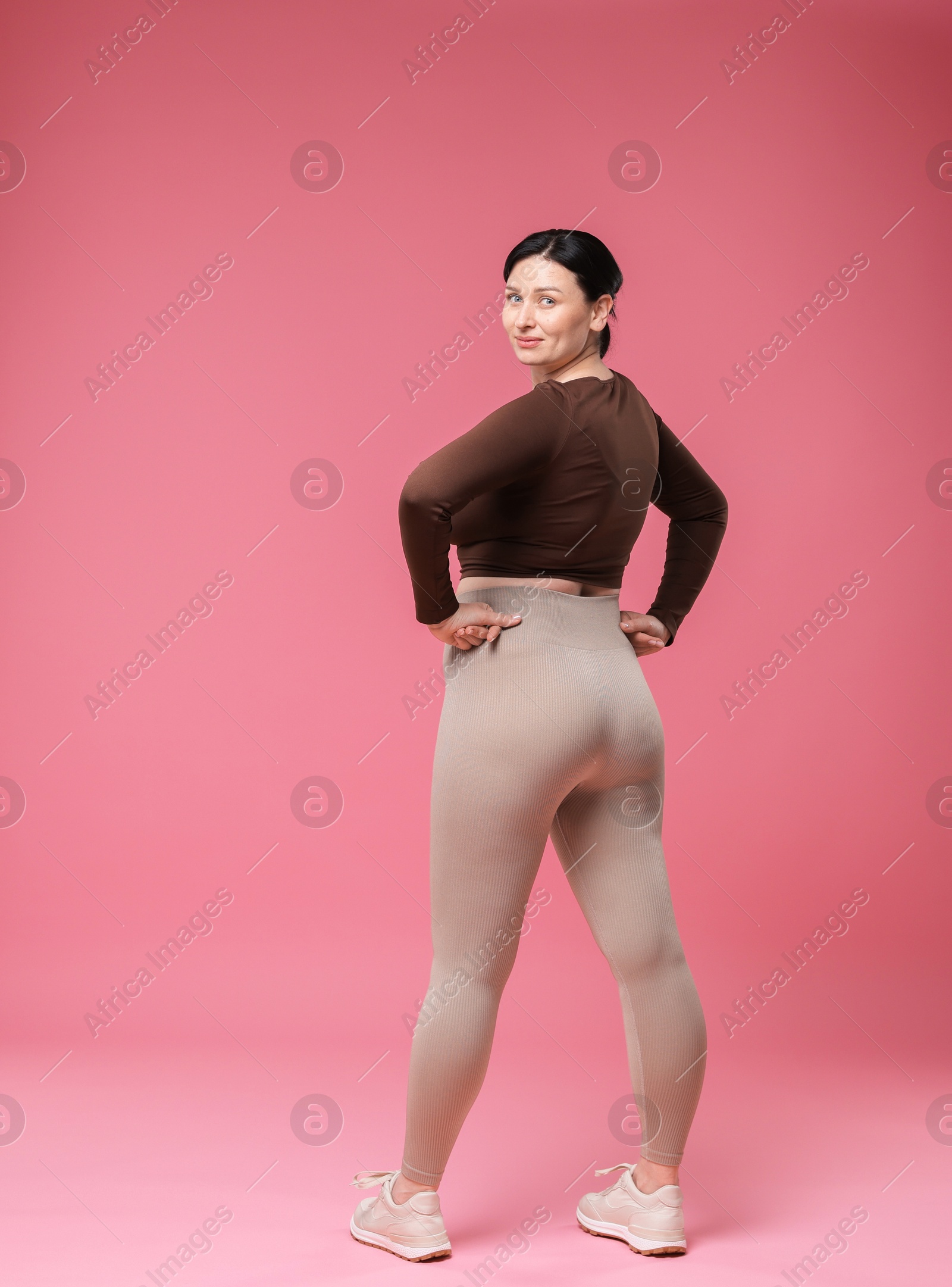 Photo of Plus size woman in gym clothes on pink background