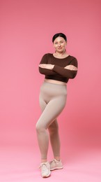 Photo of Plus size woman in gym clothes on pink background