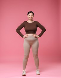 Photo of Plus size woman in gym clothes on pink background