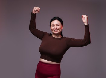 Plus size woman in gym clothes on grey background