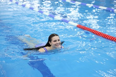 Beautiful young woman swimming in indoor pool