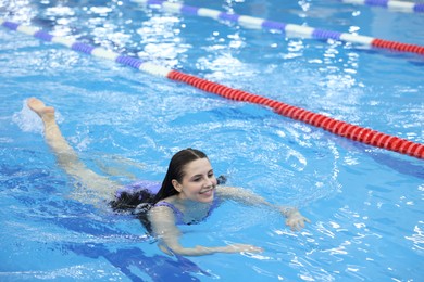 Beautiful young woman swimming in indoor pool