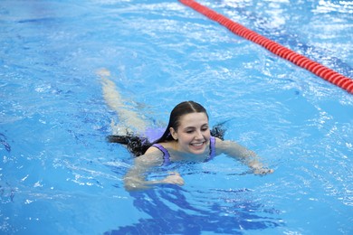 Beautiful young woman swimming in indoor pool