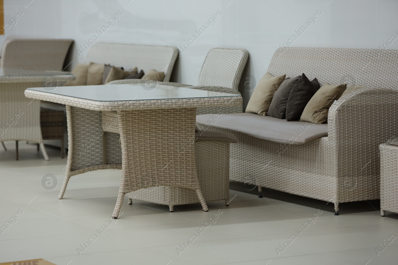 Photo of Stylish table, poufs and sofas in cafeteria