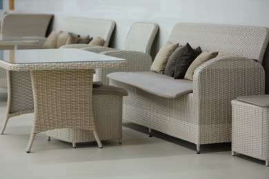 Photo of Stylish table, poufs and sofas in cafeteria