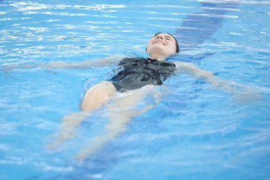 Beautiful young woman swimming in indoor pool