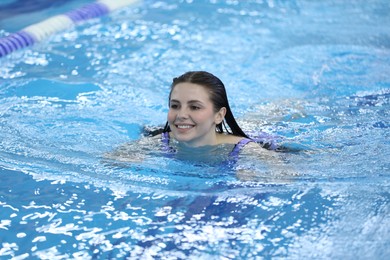 Beautiful young woman swimming in indoor pool