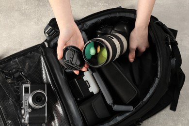 Photographer with professional equipment and backpack at light table, top view