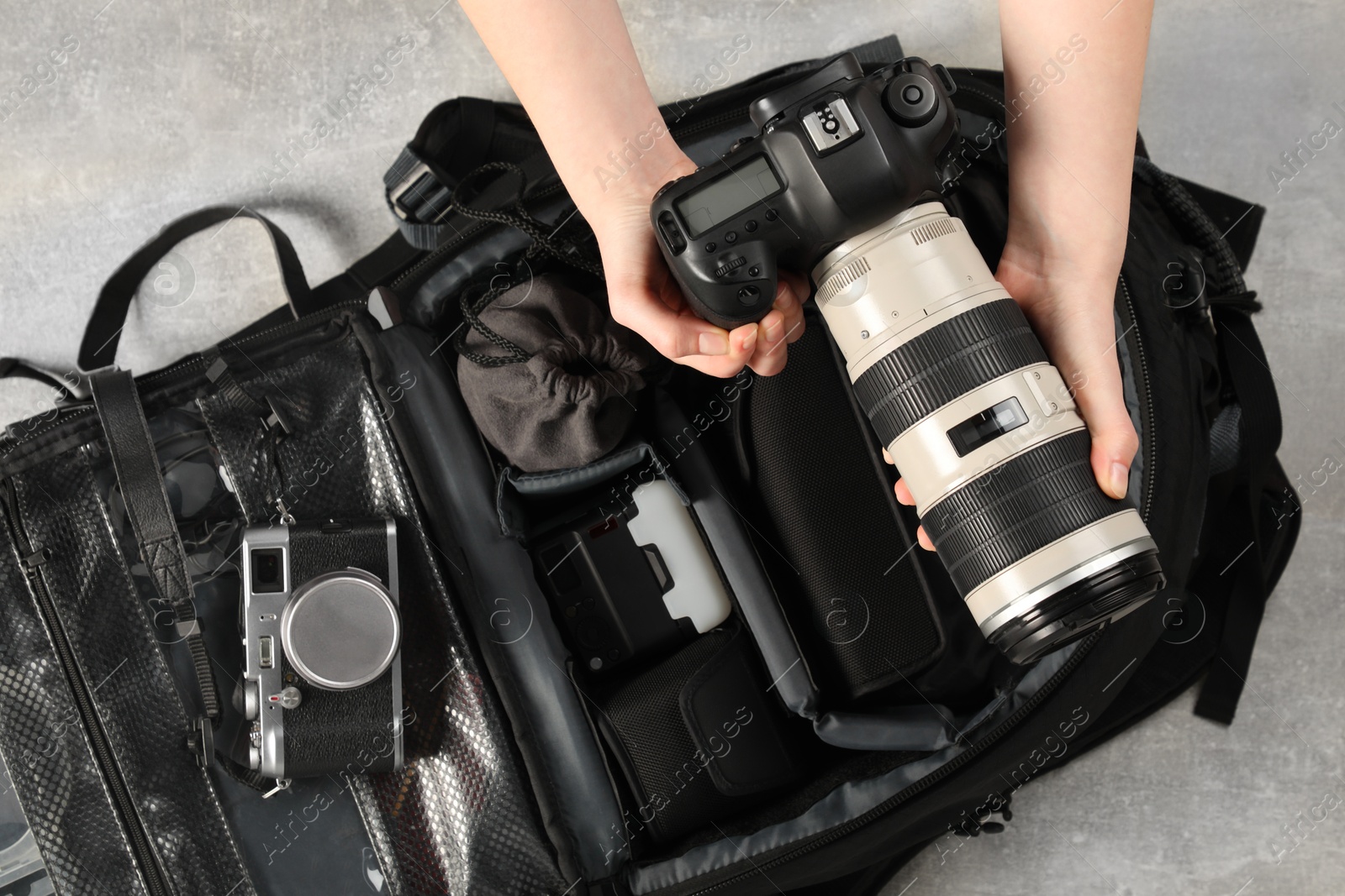 Photo of Photographer with professional equipment and backpack at light table, top view